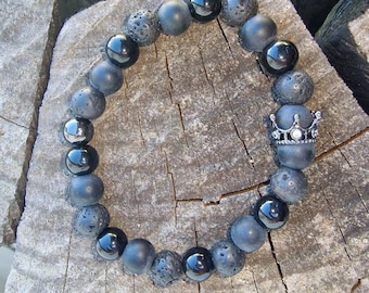 May include: Black beaded bracelet with a silver crown charm. The bracelet is made of black lava rock and onyx beads.