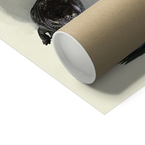 May include: A rolled-up poster with a brown exterior and white interior, resting on a light beige surface. A dark, ornate sculpture is partially visible in the upper left corner. The poster's cylindrical shape is prominent.