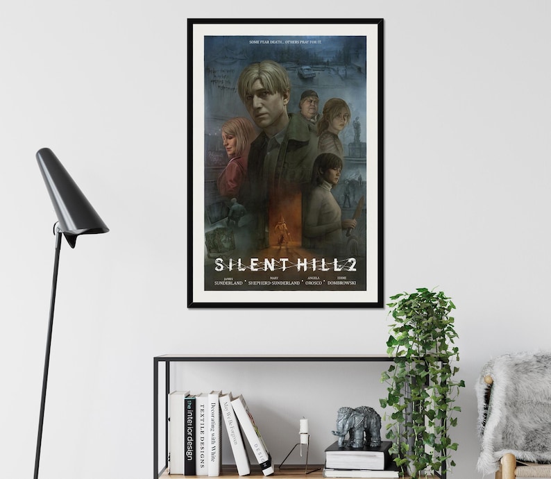 May include: A black and white poster with the title "Silent Hill 2" in a white font. The poster features a group of characters from the video game, including a man with a red shirt and a woman with a blue shirt. The poster is framed in a black frame.