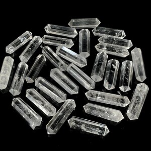 Könnte beinhalten: Eine Ansammlung von klaren, doppelt endenden Quarzkristallspitzen, die in einer Gruppe angeordnet sind. Jeder einzelne Kristall hat eine hexagonale Prismenform mit spitzen Enden und zeigt natürliche Einschlüsse sowie ein transparentes Aussehen.