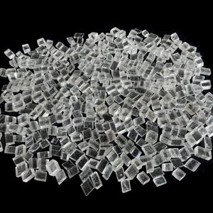 Könnte beinhalten: Ein Haufen klarer, kubischer Salzkristalle vor schwarzem Hintergrund. Die Kristalle sind klein, durchscheinend und haben ein leicht mattiertes Aussehen. Die Beleuchtung hebt die Textur und Form des Salzes hervor.