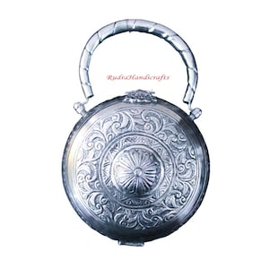 May include: A silver round box with an ornate design and a twisted handle. The box has a floral pattern and a central circular design. The text "Rudra Handicrafts" is visible on the box.