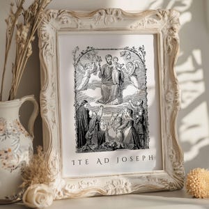 May include: A framed black and white religious print with ornate, cream-colored frame. The print depicts a biblical scene with figures, angels, and the text "ITE AD JOSEPH" at the bottom. Decorative elements include a vase and dried flowers.