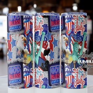 Puede incluir: Tres vasos de acero inoxidable con temática patriótica. Los vasos presentan un collage de imágenes que incluyen la Estatua de la Libertad, una bandera estadounidense, fuegos artificiales y las palabras "God Bless America" y "4th of July".
