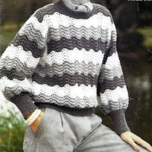 May include: A gray and white striped sweater with a wave pattern. The sweater has a round neckline and long sleeves.