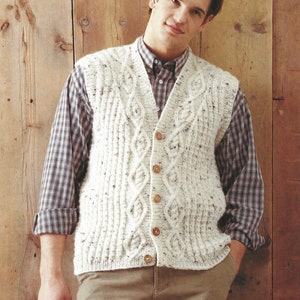May include: A white cable knit waistcoat with a button fastening. The waistcoat has a textured pattern and is worn over a checked shirt.