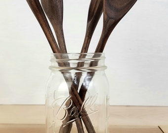 May include: Four wooden spoons in a clear glass jar with the words "Ball Mason" printed on the side.