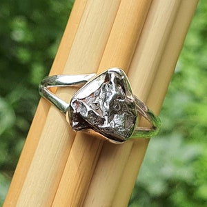 Könnte beinhalten: Ein silberner Ring mit einem rauen, strukturierten, unregelmäßig geformten Stein, der in der Mitte eingesetzt ist.