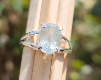 May include: A silver ring with a light blue oval gemstone. The ring has a delicate, open design.