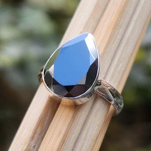 May include: A silver ring with a black pear-shaped gemstone.