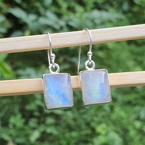 May include: A pair of silver dangle earrings with iridescent moonstone rectangular stones.