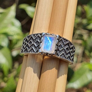 Könnte beinhalten: Ein silberner Ring mit geometrischem Muster und einem rechteckigen Mondstein.