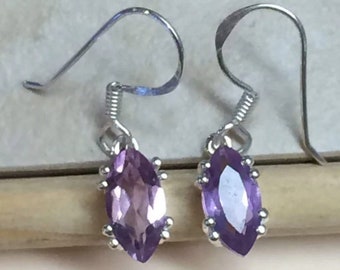 May include: A pair of silver earrings featuring marquise-shaped amethyst gemstones. The earrings have a simple, elegant design.