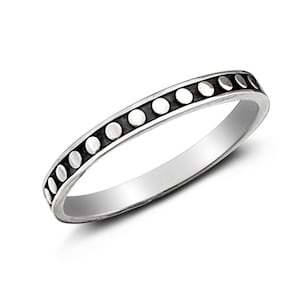 Puede incluir: Un anillo de plata con una banda de pequeños círculos en relieve alrededor del borde.