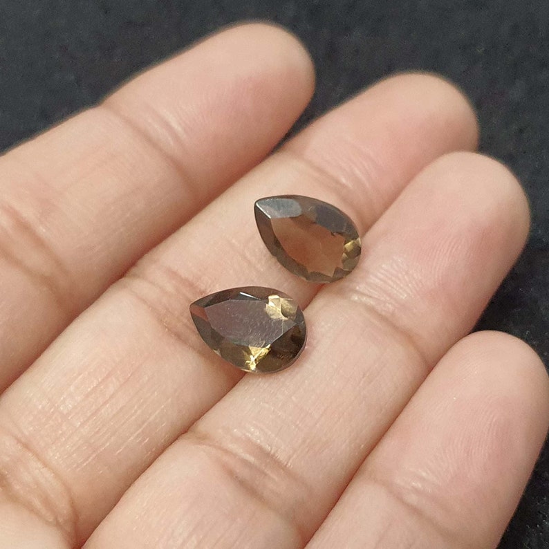 May include: Two pear-shaped brown gemstones with a faceted cut.