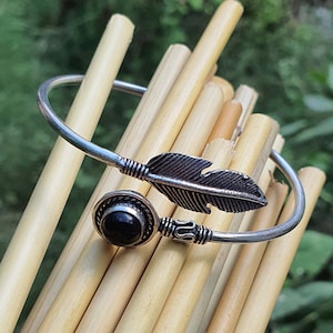 Op de afbeelding: Zilveren armband met een zwarte edelsteen en een veren ontwerp.