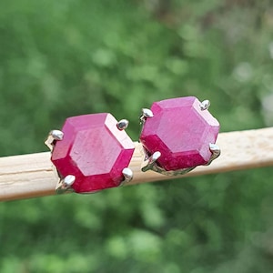 May include: A pair of silver stud earrings with hexagonal red ruby gemstones.