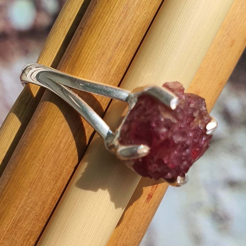 Puede incluir: Un anillo de plata con una gran piedra preciosa rosa en bruto. La piedra preciosa est&aacute; engastada en una banda de plata sencilla.