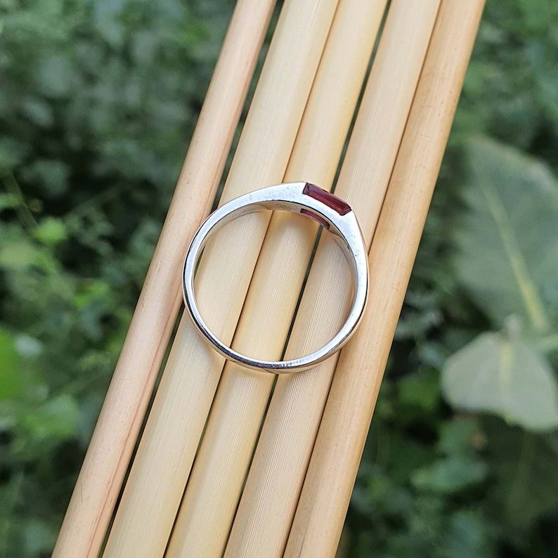 May include: A silver ring with a rectangular red gemstone set in the band.