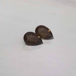May include: Two pear-shaped brown gemstones on a white background.