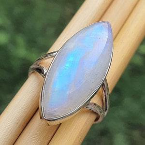 May include: A silver ring with a large, iridescent moonstone set in a marquise shape.