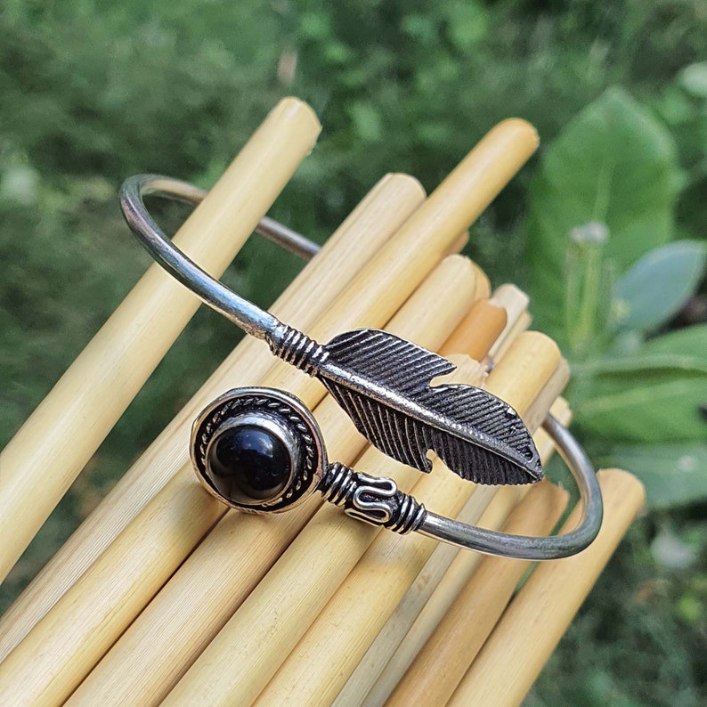 Op de afbeelding: Zilveren armband met een zwarte edelsteen en een veren ontwerp.
