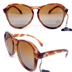 Könnte beinhalten: Braune Schildpatt-Sonnenbrille mit braunen Verlaufsgläsern. Die Sonnenbrille hat ein Blumendetail an der Seite und ein Etikett mit der Aufschrift "Mary Quant".