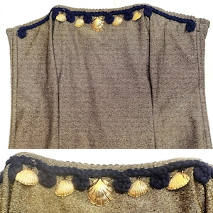 May include: A gold strapless dress with a black and gold trim. The trim is decorated with gold seashells.