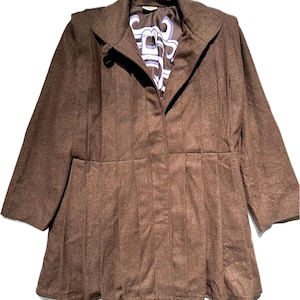 Puede incluir: Una chaqueta de lana marrón con falda plisada y cierre de cremallera. La chaqueta tiene un cuello alto y un interior forrado con un diseño estampado en azul y blanco.