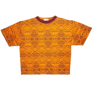 Könnte beinhalten: Orangefarbenes T-Shirt mit kurzen Ärmeln und einem braunen geometrischen Muster.