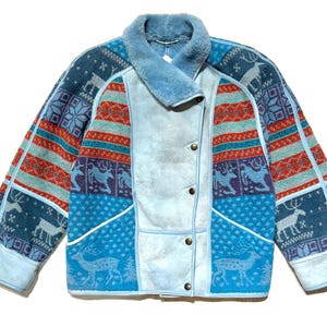 May include: A white ceramic mug with a black handle and the text "But First, Coffee" in a bold, black font. The mug is set against a blurred background, suggesting a cozy setting.