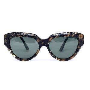 Puede incluir: Un par de gafas de sol de carey negro y dorado con lentes oscuros.