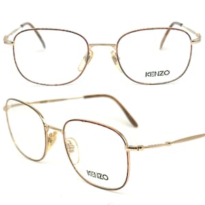 Op de afbeelding: Gouden metalen bril met een rechthoekig montuur en bruine accenten. De merknaam "KENZO" staat op de rechterlens gedrukt.