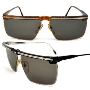 May include: Two pairs of sunglasses, one with a brown tortoise shell frame and gold accents, and the other with a black frame and silver accents. Both pairs have dark lenses.
