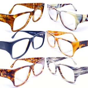 Op de afbeelding: Zes brillen met verschillende gekleurde monturen en glazen. De monturen zijn gemaakt van schildpad, zwart en bruin plastic. De glazen zijn helder. De merknaam "Vivienne la Robie" staat op de monturen gedrukt.