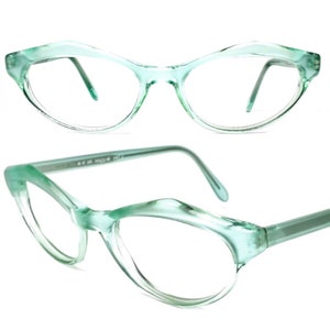 Puede incluir: Un par de gafas de pasta de color verde menta con forma de ojo de gato y lentes transparentes. Las gafas tienen un estilo retro.