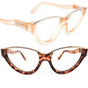 Puede incluir: Dos pares de gafas de ojo de gato. El par superior es de color melocotón con un puente de metal plateado. El par inferior es de carey marrón con un puente de metal dorado.