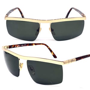May include: Gold-tone sunglasses with tortoiseshell arms and dark green lenses. The sunglasses have a rimless design with a thin gold metal frame.