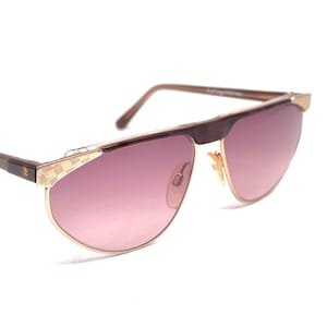 May include: A pair of gold-tone aviator sunglasses with brown tortoise shell frames and pink gradient lenses.