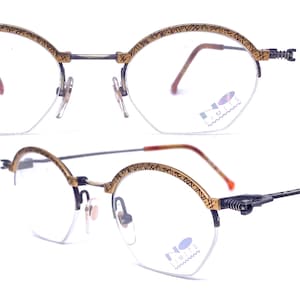 Könnte beinhalten: Vintage Brille mit goldfarbenem Rahmen und klaren Gläsern. Die oberen Ränder weisen ein geätztes Design auf. Die Bügel sind schwarz mit einem Federscharnier. Auf den Gläsern steht "NO LIMITS".