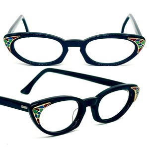 Könnte beinhalten: Schwarze Cat-Eye-Brille mit goldenem Rahmen und bunten Emaille-Akzenten an den Bügeln.