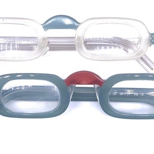 May include: Two pairs of eyeglasses with rectangular frames. The top pair has clear frames with gray lenses. The bottom pair has gray frames with red accents and clear lenses. The bottom pair has the text "C. 02 38 037  NIR 12" printed on the right arm.