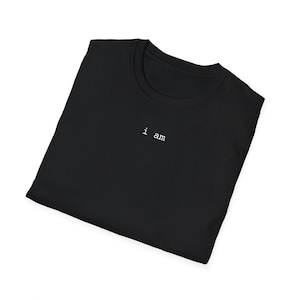 以下が含まれることがあります： 胸に白で「i am」と刺繍された黒いTシャツ。Tシャツは折りたたまれており、クルーネックとミニマルなデザインが特徴です。生地は柔らかく快適に見えます。
