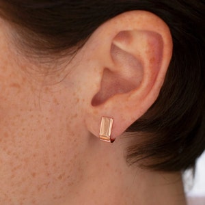 gold hoop earrings with stud fitting on women ear.