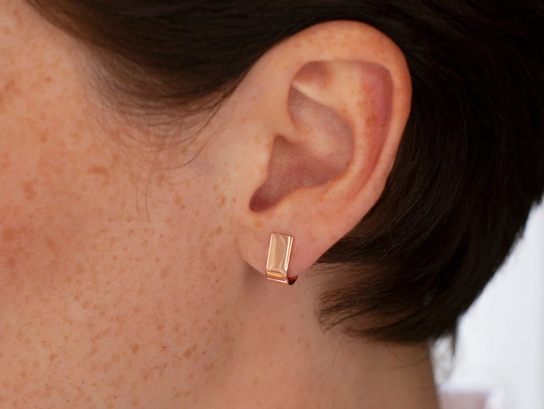 gold hoop earrings with stud fitting on women ear.