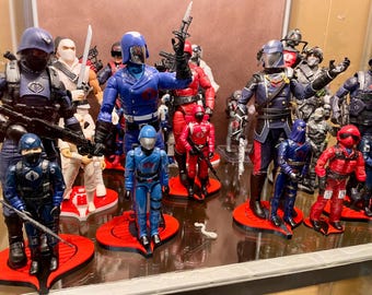 Peut inclure: Une collection de figurines d'action bleues et rouges avec des accents noirs et argentés. Les figurines sont debout sur des socles rouges et noirs avec un logo de cobra.
