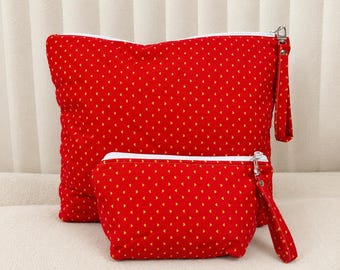 May include: A set of two red zippered pouches featuring a repeating pattern of small yellow hearts. Each pouch includes a white zipper closure and a matching red fabric wrist strap attached to the side with a silver-toned metal clasp hardware.