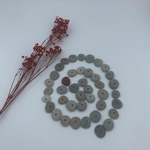 May include: A spiral of gray and brown stones with a single red stone in the center. The stones are arranged in a circle, with the red stone in the middle. The stones are all different sizes and shapes.