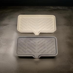 May include: Two plastic dish drying racks, one white and one gray, with a diagonal pattern. The racks have a raised lip on the front and a drainage spout on the back.