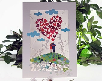 May include: A white card with a red heart made of smaller hearts, a couple standing on a green hill with flowers, and blue clouds. The card has a delicate, intricate design.